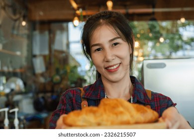 Cafe worker hand out small tray with croissants in it, which is tray for serving customers who sit eat in store, for convenience sitting eating, handed over camera that was filming her. - Powered by Shutterstock