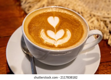 Cafelatte coffee served in a white cup and flower topping                  