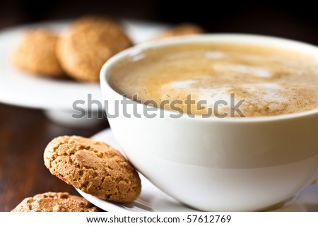 Caffe Latte. Cup of coffee with a sweet cookie. Symbolic image. Rustic wooden background. Close up. 
