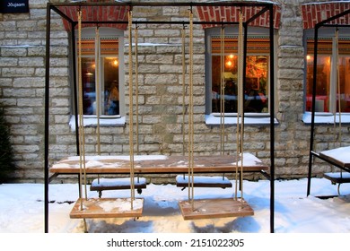 Caffe terrace covered with snow in a loft design style with swings as chairs. Selective focus. High quality photo
