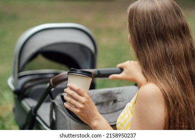 Caffeine And Breastfeeding. Young Mom With Coffee To Go Cup Walk With Newborn Son. Mother Walk With Newborn Baby In Stroller While Drinking Take Away Coffee.