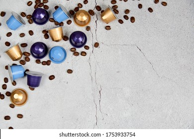 Caffeine, hot drinks and objects concept - close up colorful capsules or pods for coffee mashine with some roasted grains on gray concrete background. Top view with space for text. Selective Focus.
