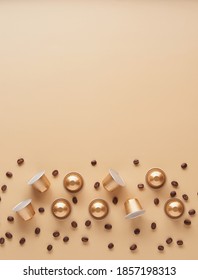 Caffeine, hot drinks and objects concept - close up of golden capsules or pods for coffee mashine with some roasted grains on beige background. Top view with space for text. Flat lay..