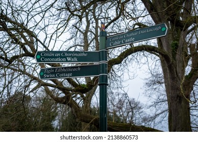 Cahir, Ireland - Feb 17 2022: Tourist Multidirectional Way Finding Sign Post On 17 Feb 2022 At Cahir Castle In Tipperary, Ireland, Pointing To Popular Destinations Cahir Castle And Swiss Cottage. 