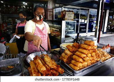 Cainta, Rizal, Philippines - July 10, 2020: Woman sells assorted snack food items at her snack bar along a sidewalk.