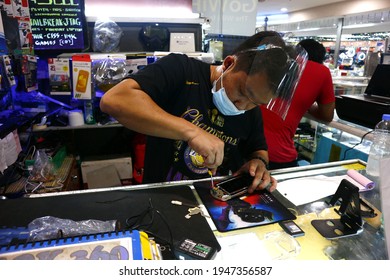 Cainta, Rizal, Philippines - November 15, 2020: Cellphone And Gadget Technican Fix An Electronic Gadget For A Customer At His Stall.