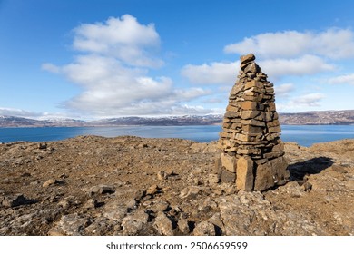 Cairn, human-made pile of stones making the trail in Westfjords, Iceland, with sea view and snowcapped mountains in the background.  - Powered by Shutterstock