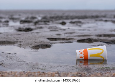 Cairns, Australia - June 16, 2019: McDonald's Cup Littered On Sandy Beach.