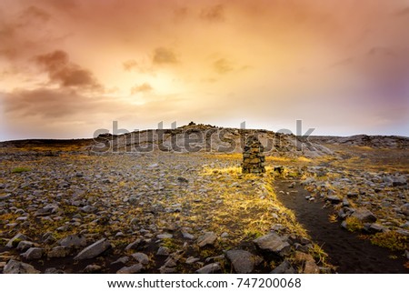 Cairns, piles of volcanic stones in Iceland, near a volcanic sand pathway