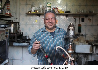 CAIRO, EGYPT - CIRCA APRIL 2017: Portrait of a happy Egyptian man who offers hookah (shisha) to his customers in his small traditional bar in Islamic Cairo.