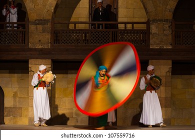 Cairo, Egypt - July 3, 2010: Egyptian Sufi dancer twirling and spinning in a motion blurred whirling dervish at an open air courtyard performance at Al Ghouri in Islamic Cairo