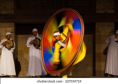 Cairo, Egypt - July 3, 2010: Male Egyptian Sufi dancer in yellow spinning a colorful circular sheet during whirling dervish at open air courtyard performance, Al Ghouri, in Islamic Cairo