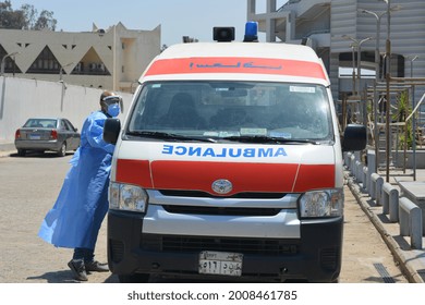 Cairo, Egypt, July 7 2021: Egyptian Health Worker In A Blue Protective Gown, Double Face Mask And Face Shield Beside An Equipped Ambulance Car Ready To Deal With Covid-19 Coronavirus Emergency Cases