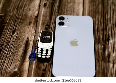 Cairo, Egypt, June 11 2022: Apple IPhone 11 With 6.1inch Liquid Retina HD High Definition Display And A Tiny Small Old Mini Nokia Cell Phone With A Keypad Isolated On Wood Background, Selective Focus