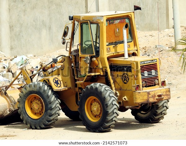Cairo, Egypt, March 9 2022: heavy yellow bulldozer,\
grader and excavator construction equipment, end loader vehicle,\
bulldozer quarry machine, stone wheel yellow digger cleaning\
construction waste