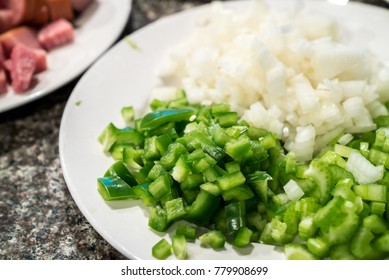 A Cajun Mirepoix Of Onion, Celery, And Green Bell Pepper, Sits Diced And Prepped On A White Plate To Be Used In A Jambalaya Recipe.  Also Known As The Holy Trinity In Creole Cooking.