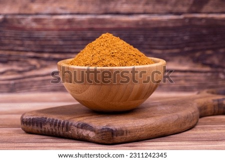 Cajun spice powder on wooden background. Powdered dried cajun in wooden bowl