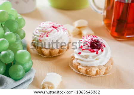 Cake basket with tea white chocolate and grapes. On a yellow background