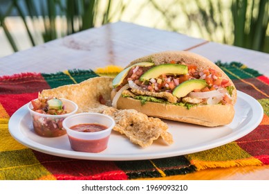 cake called guacamaya, traditional Mexican food, avocado, tomato, hot sauce, chicharron, with drink, natural background window and plants  - Shutterstock ID 1969093210