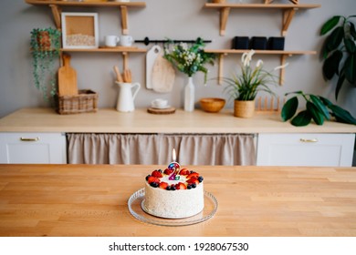 cake with candle number two and fruit on the table on the Scandinavian-style kitchen interior. minimalist and light interior. design of the photo studio. furniture made of wood.