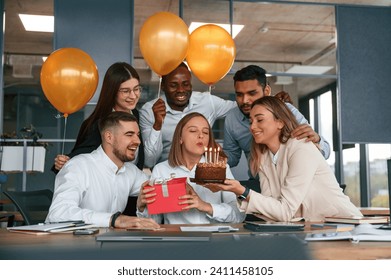 Cake with candles. Employee having a birthday in the office, group of workers. - Powered by Shutterstock