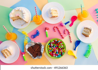 Cake, Candy, Chocolate, Whistles, Streamers, Balloons, Juice On Holiday Table. Concept Of Children's Birthday Party. View Top.