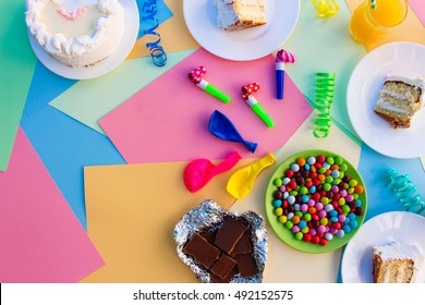 Cake, candy, chocolate, whistles, streamers, balloons, juice on holiday table. Concept of children's birthday party. View top.