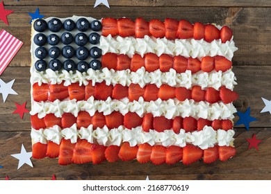 Cake with the colors of the US flag on a wooden background with flags and stars decoration. Copy space. Independence Day Celebration. Top view.