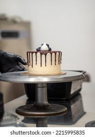 Cake Designer Decorating A Chocolate Drip Cake With Meringue And Blueberries