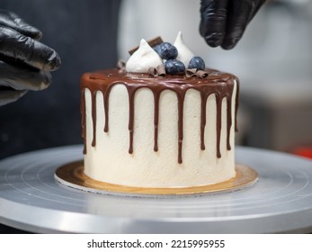 Cake Designer Decorating A Chocolate Drip Cake With Mering And Blueberries