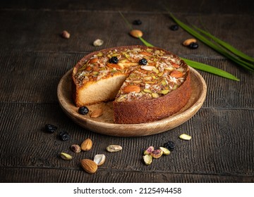 Cake. Mawa cake is a rich, delicious cake made with mawa and atta. serve on wood background with dry fruit nuts. Homemade round half cut sponge cake. Almond, Cashew, Blackberry, Pistachio.  - Powered by Shutterstock