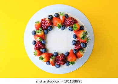 Cake On Birthday Decorated With Strawberry, Blueberry, Pomegranate, On A Yellow Background. Top View.