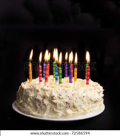 cake on a black background with candles alight