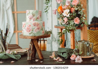 Cake on wooden stand with flowers and tubes of paint tubes, beautiful vintage room