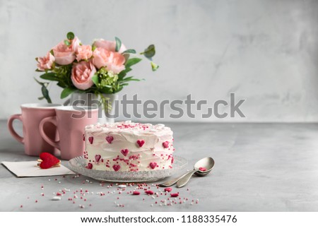Cake with small hearts and colorful sprinkles on a plate with  two cups of coffee. Grey stone background. Romantic love background. Valentine's day, Mother's Day, Birthday Cake card.
