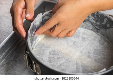A cake tin line with wax paper and wrap in aluminum foil on a tray for putting a water bath before baking a cheesecake in the oven.