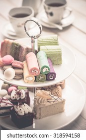 Cakes And Macaroons On Two Tiered Tray With Teapot And Cup Background. Afternoon Tea