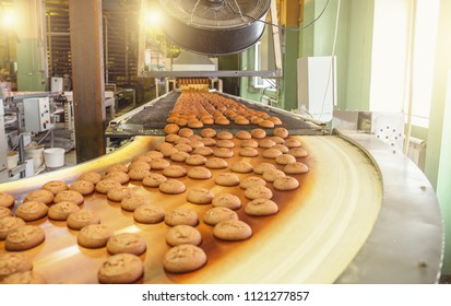 Cakes On Automatic Conveyor Belt Or Line, Process Of Baking In Confectionery Culinary Factory Or Plant. Food Industry, Cookie And Other Sweet Breadstuff Production. Close Up