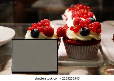 Cakes on a bakery window with berries and an empty price tag next to it. Sale of confectionery concept.