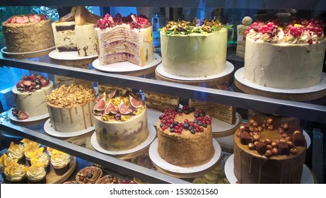 Cakes On Display In Cake Shop. Lots Of Fruitcakes And Cupcakes In Showcase Of Pastry Shop. Different Sweets For Sale
