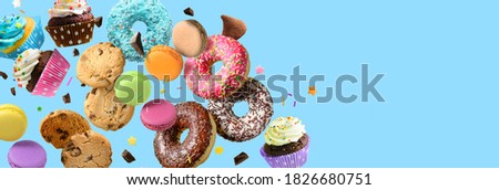 Cakes, sweets, confectionery collage background. Donuts, cookies cupcakes macaroons flying over blue background