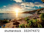 Cala dHort Beach at sunset. People sunbathing, have a party on the sandy tropical picturesque rocky beach during sunset. This beach is very popular for clubbers and vacationers Balearic Islands. Ibiza