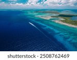 Calabash Caye, Turneffe Atoll in Belize - aerial drone image of a speeding motorboat and the reef at Turneffe Atoll Marine Reserve