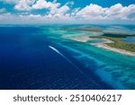 Calabash Caye, Turneffe Atoll in Belize - aerial drone image of a speeding motorboat and the reef at Turneffe Atoll Marine Reserve