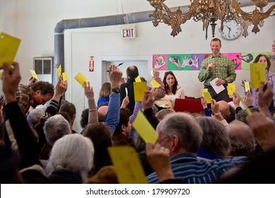 Calais, Vermont, USA - March 4, 2014: Voters Raise Yellow Cards To Register Their Vote On This Vote From The Floor At The Calais Town Hall During The School Board Meeting On Town Meeting Day.