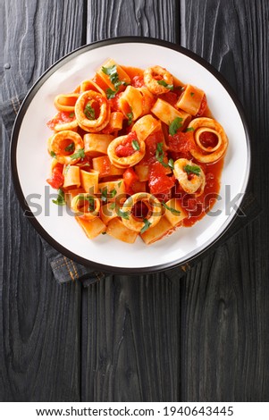 Calamarata pasta with squid sauce a traditional neapolitan recipe close-up in a plate on the table. vertical top view from above
