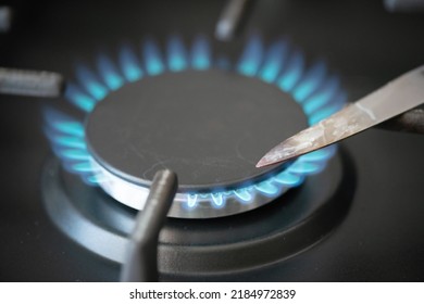 Calcining A Kitchen Knife On A Gas Stove Burner Close Up.