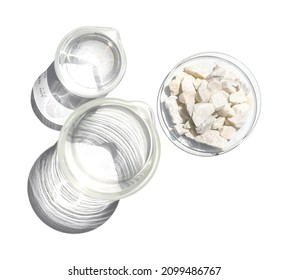 Calcium Carbonate Chip In Chemical Watch Glass Place Next To Crystal Clear Liquid In Beaker. Closeup Chemical Ingredient On White Laboratory Table. Top View