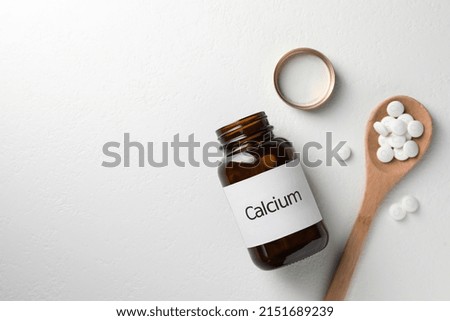 Calcium supplement pills on white table, flat lay. Space for text