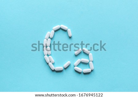 Calcium Tablets. White pills forming shape to Ca alphabet on blue background, copy space, top view.